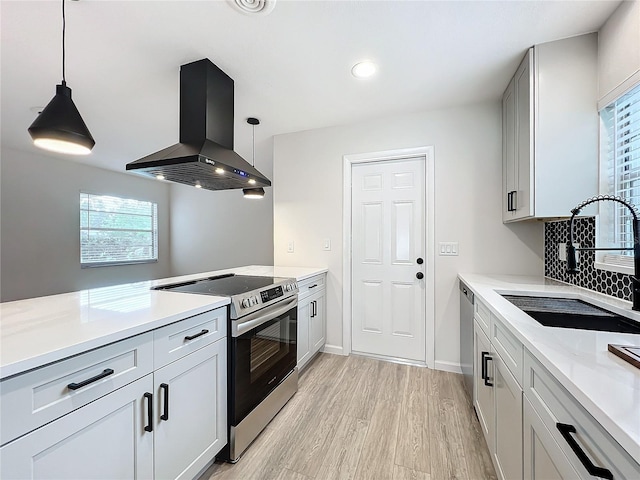 kitchen with stainless steel appliances, sink, decorative light fixtures, and wall chimney exhaust hood