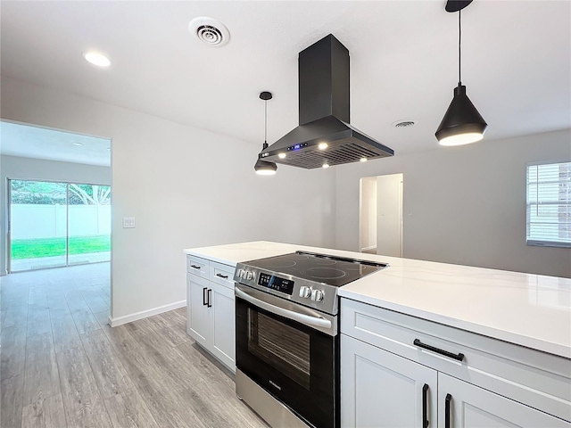 kitchen featuring white cabinets, hanging light fixtures, electric stove, and island exhaust hood