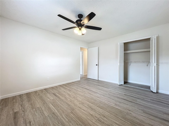 unfurnished bedroom with a closet, ceiling fan, wood-type flooring, and a textured ceiling