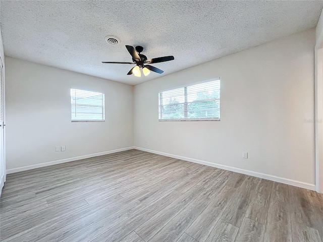 unfurnished room with a healthy amount of sunlight, ceiling fan, a textured ceiling, and light hardwood / wood-style flooring