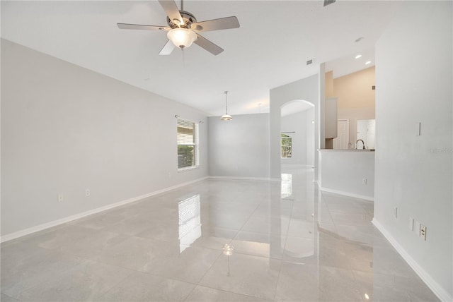 tiled empty room featuring vaulted ceiling and ceiling fan