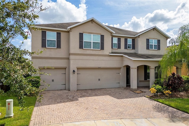 view of front of house featuring stucco siding, decorative driveway, and a garage