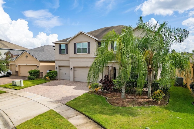 view of front of house with a garage, central AC unit, and a front lawn