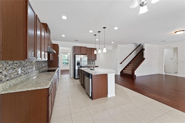 kitchen featuring under cabinet range hood, open floor plan, light tile patterned floors, appliances with stainless steel finishes, and a sink