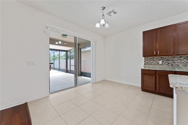 interior space featuring light tile patterned floors, baseboards, visible vents, and a textured ceiling