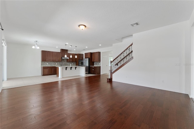 unfurnished living room featuring visible vents, baseboards, stairway, recessed lighting, and light wood-style flooring