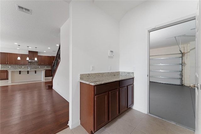 bar with visible vents, under cabinet range hood, decorative backsplash, recessed lighting, and hanging light fixtures