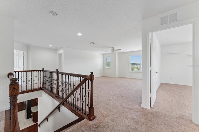 corridor featuring carpet flooring, an upstairs landing, visible vents, and baseboards