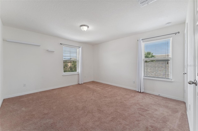 spare room with visible vents, light colored carpet, and a textured ceiling