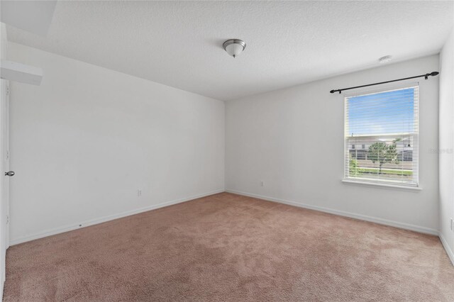 carpeted empty room with a textured ceiling and baseboards