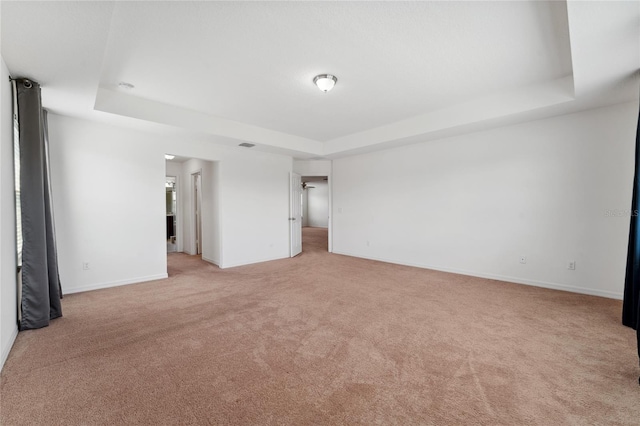 spare room featuring a tray ceiling, light carpet, baseboards, and visible vents