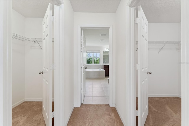 spacious closet featuring light tile patterned flooring, visible vents, and light carpet