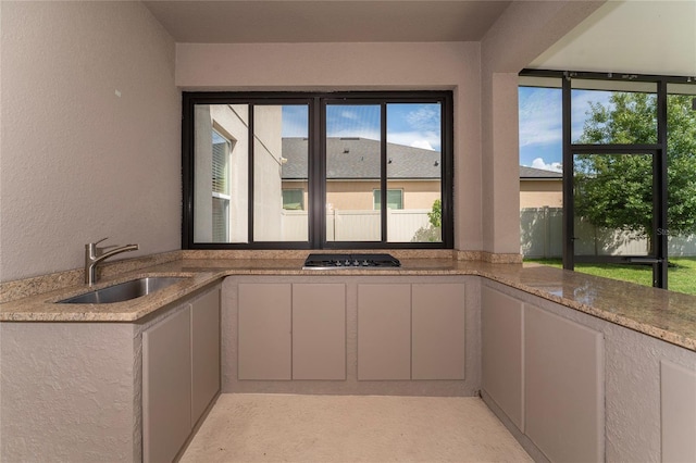 kitchen with gas cooktop, a textured wall, and a sink