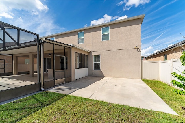 rear view of house with glass enclosure, a patio, a ceiling fan, fence, and stucco siding