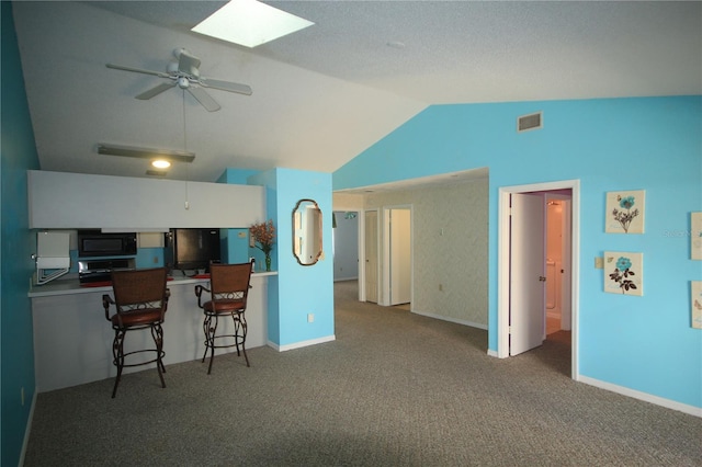 kitchen featuring a breakfast bar area, black microwave, white cabinets, kitchen peninsula, and ceiling fan