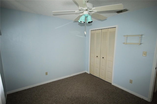 unfurnished bedroom with dark colored carpet, ceiling fan, and a closet