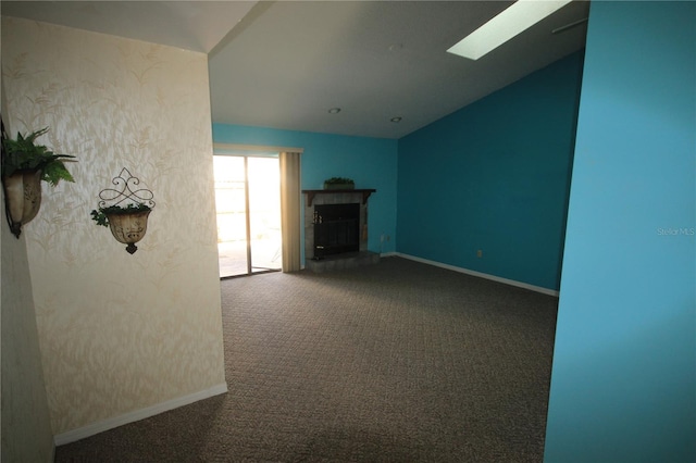 unfurnished living room with vaulted ceiling with skylight and carpet flooring