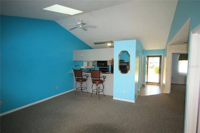 kitchen featuring a kitchen breakfast bar, white cabinetry, lofted ceiling, ceiling fan, and light carpet