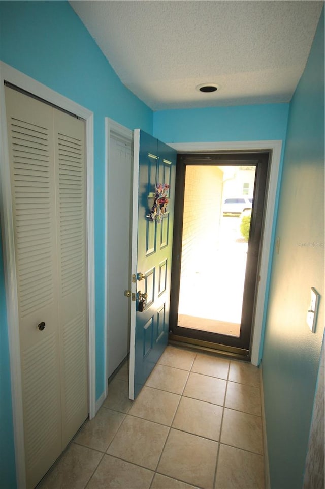 doorway featuring a textured ceiling and light tile patterned floors