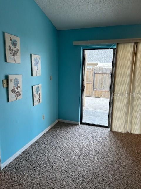 carpeted empty room featuring a textured ceiling