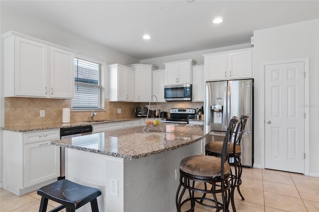 kitchen with a breakfast bar, white cabinetry, appliances with stainless steel finishes, and a kitchen island