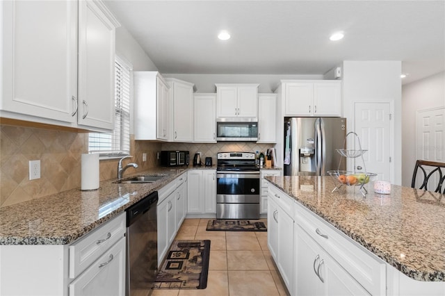 kitchen with light tile patterned flooring, sink, white cabinets, a kitchen island, and stainless steel appliances