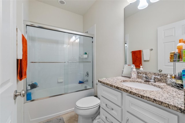 full bathroom with combined bath / shower with glass door, vanity, toilet, and tile patterned floors