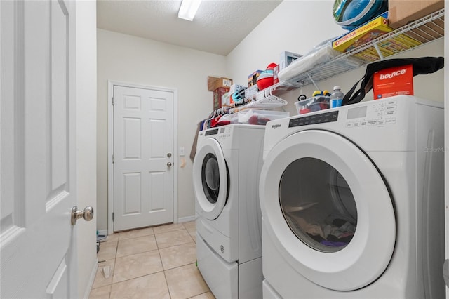 washroom with a textured ceiling, light tile patterned floors, and washing machine and dryer