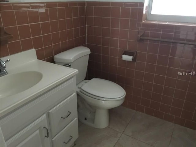 bathroom featuring tile walls, toilet, vanity, and tile patterned floors