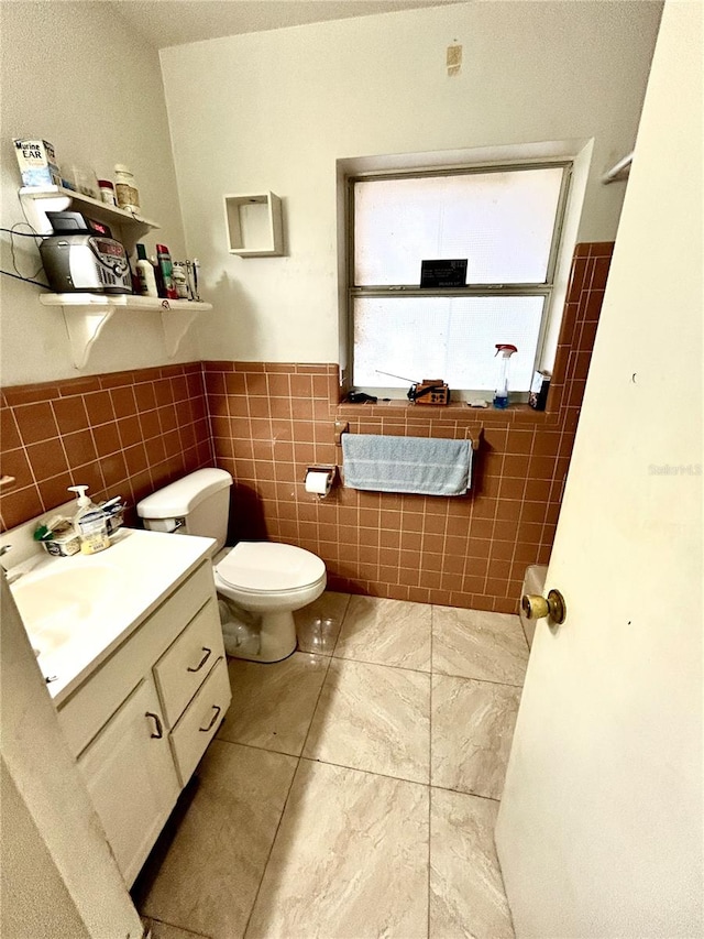 bathroom with vanity, tile patterned floors, toilet, and tile walls