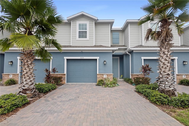 1820 Holden Ridge Ln, Clermont, FL 34715 - townhome / multi-family property with decorative driveway, stone siding, an attached garage, and stucco siding