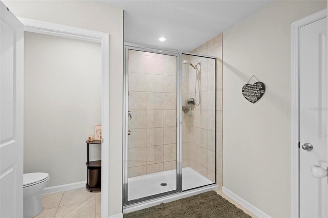 bathroom with toilet, an enclosed shower, and tile patterned floors