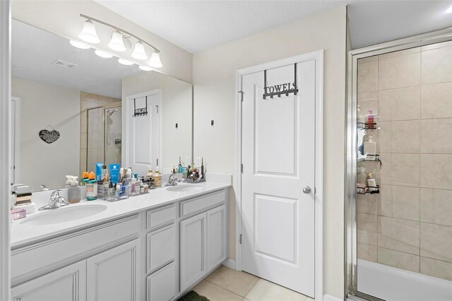 bathroom with a shower with door, vanity, and tile patterned floors