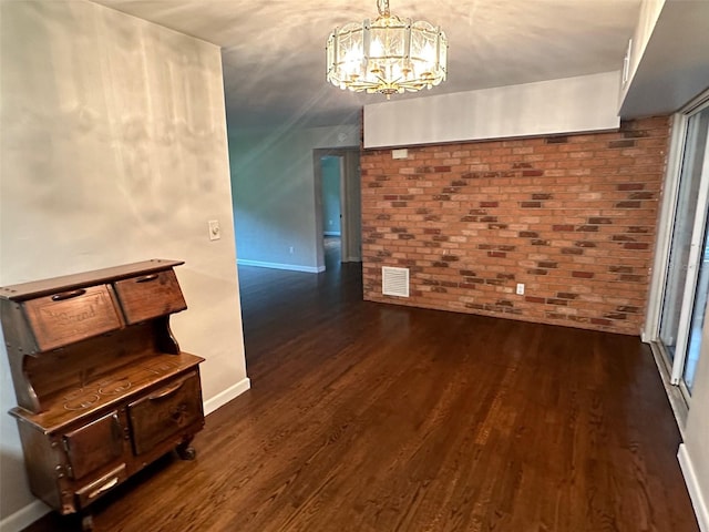 interior space with dark hardwood / wood-style floors, a chandelier, and brick wall