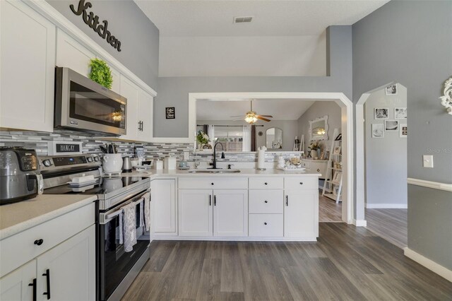 kitchen featuring decorative backsplash, white cabinets, dark wood-type flooring, and stainless steel appliances