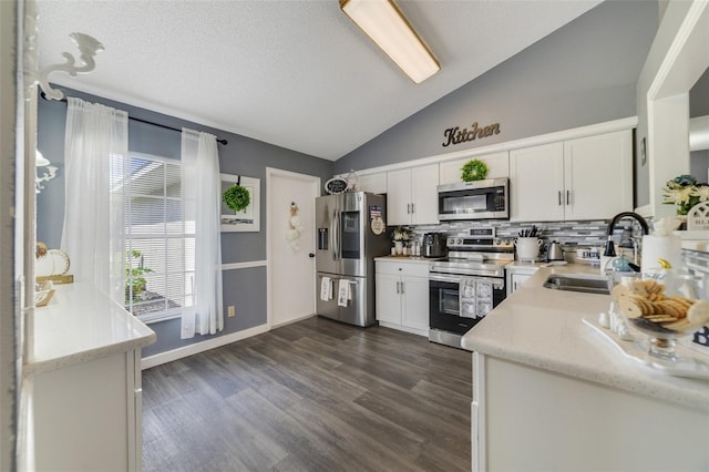 kitchen featuring appliances with stainless steel finishes, sink, white cabinetry, vaulted ceiling, and dark hardwood / wood-style floors