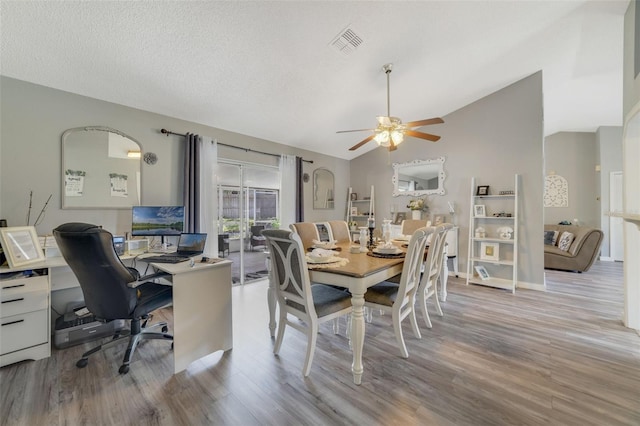 dining area featuring light hardwood / wood-style floors, lofted ceiling, a textured ceiling, and ceiling fan