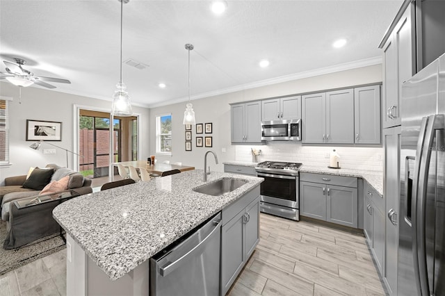 kitchen featuring decorative light fixtures, stainless steel appliances, an island with sink, ceiling fan, and sink