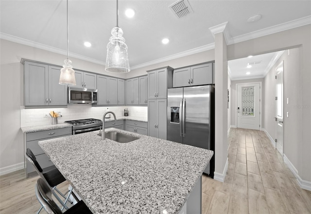 kitchen with light stone countertops, a center island with sink, appliances with stainless steel finishes, sink, and light wood-type flooring