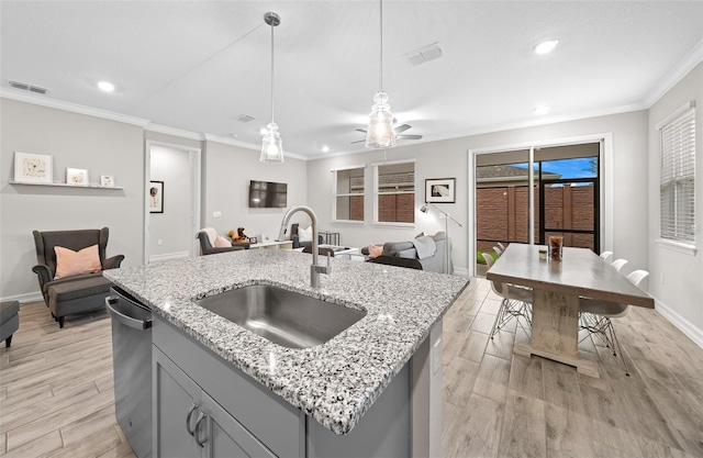 kitchen featuring light stone counters, light hardwood / wood-style floors, sink, gray cabinets, and pendant lighting