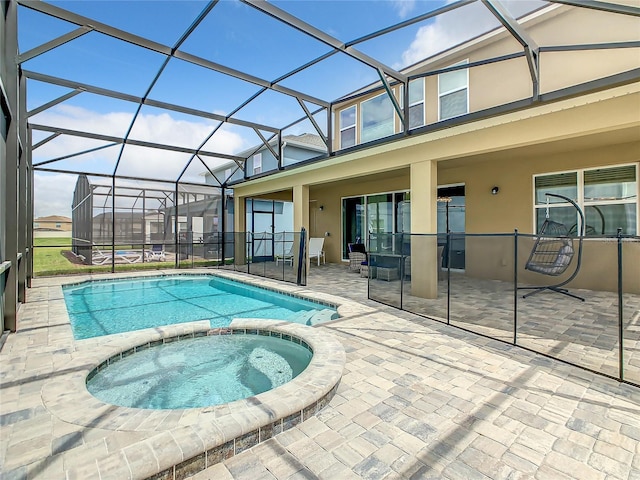 view of swimming pool with glass enclosure, an in ground hot tub, and a patio