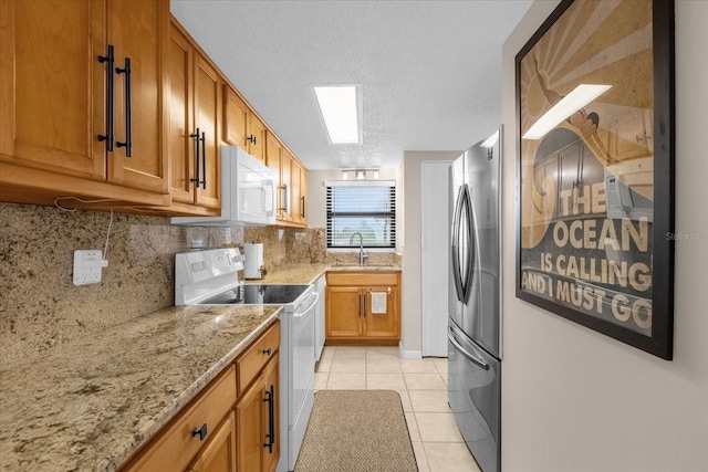 kitchen with white appliances, a textured ceiling, light tile patterned floors, sink, and light stone countertops