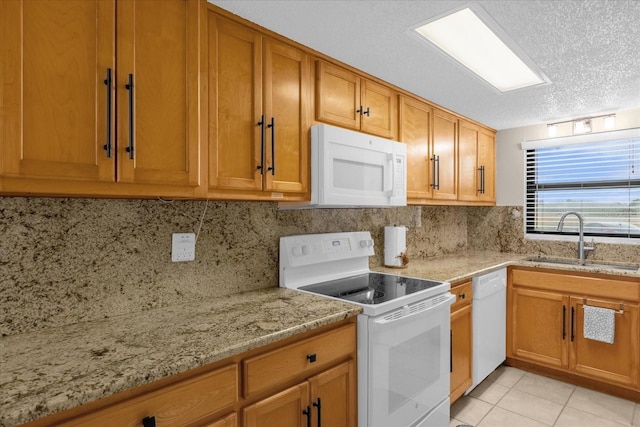 kitchen featuring backsplash, light tile patterned floors, white appliances, light stone counters, and sink