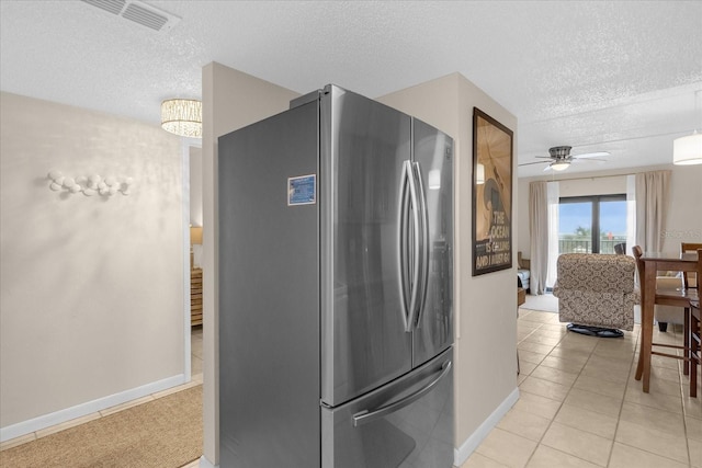 kitchen featuring a textured ceiling, ceiling fan, stainless steel refrigerator, and light tile patterned flooring