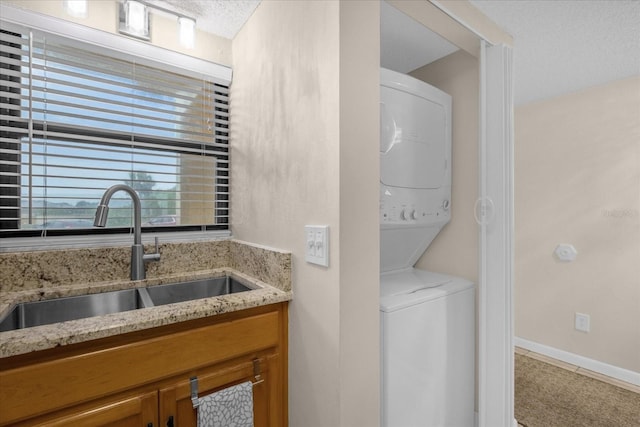 interior space featuring light carpet, stacked washing maching and dryer, a textured ceiling, and sink