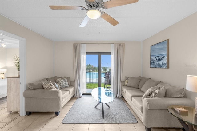 living room with ceiling fan, a water view, and light tile patterned flooring