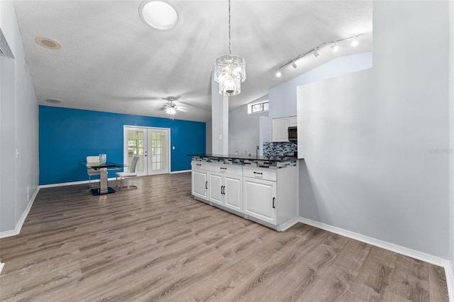 kitchen featuring light hardwood / wood-style flooring, french doors, hanging light fixtures, white cabinetry, and lofted ceiling