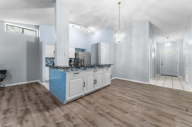 kitchen with a textured ceiling, white cabinetry, hanging light fixtures, stainless steel refrigerator with ice dispenser, and light hardwood / wood-style floors