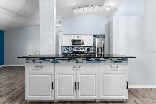 kitchen with vaulted ceiling, appliances with stainless steel finishes, light hardwood / wood-style floors, sink, and white cabinetry