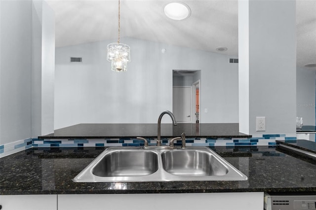 kitchen featuring vaulted ceiling, dishwasher, hanging light fixtures, sink, and dark stone counters